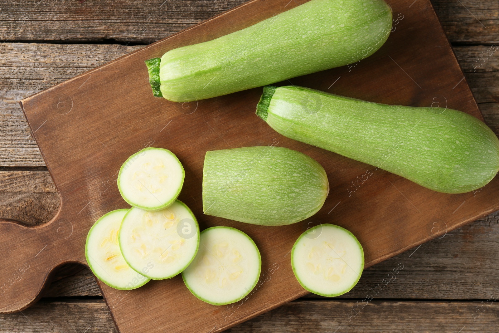 Photo of Board with fresh zucchinis on wooden table, top view