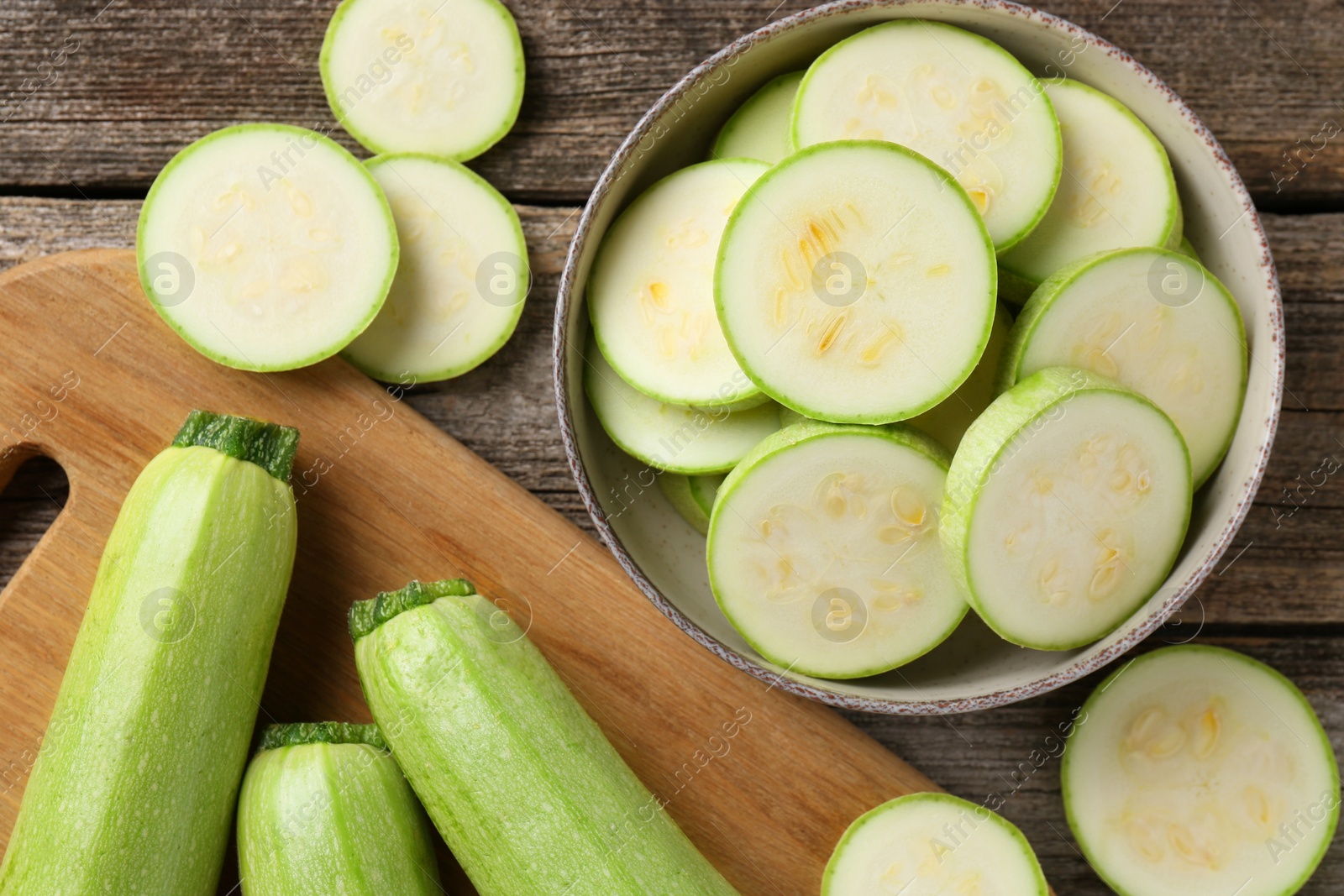 Photo of Fresh whole and cut zucchinis on wooden table, flat lay