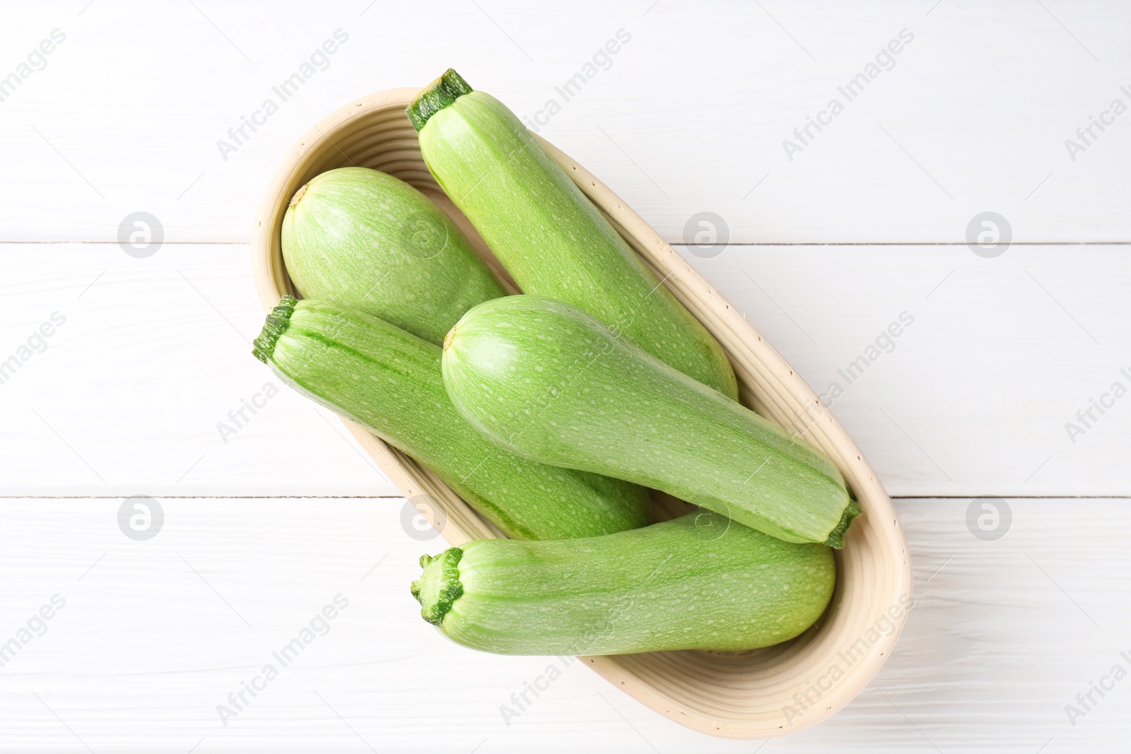 Photo of Fresh zucchinis on white wooden table, top view