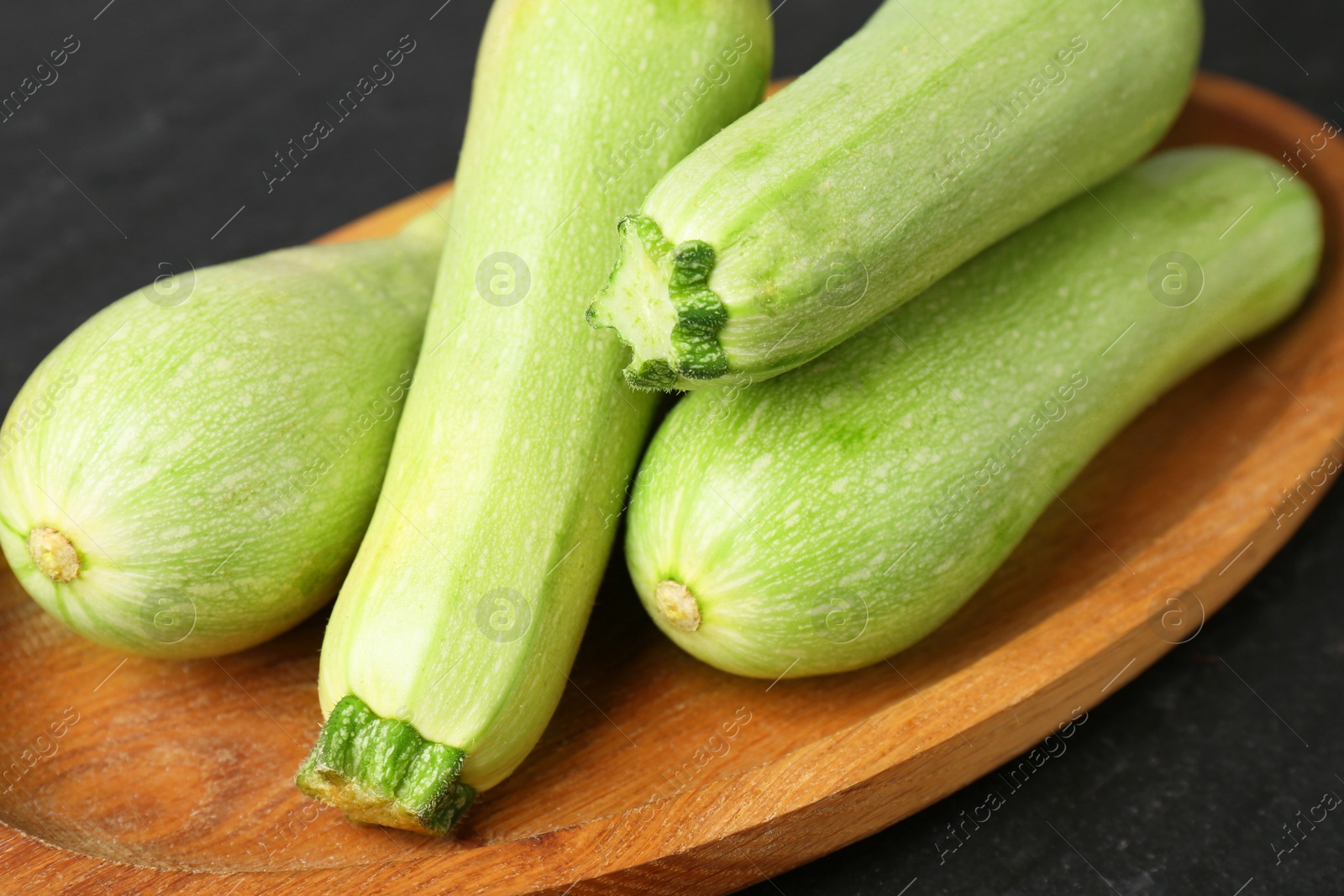 Photo of Fresh ripe zucchinis on dark table, closeup