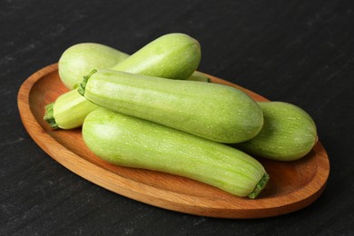 Photo of Fresh zucchinis on dark textured table, closeup