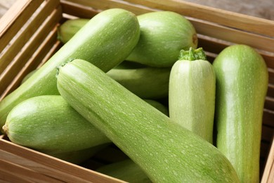 Photo of Fresh ripe zucchinis in wooden crate, closeup