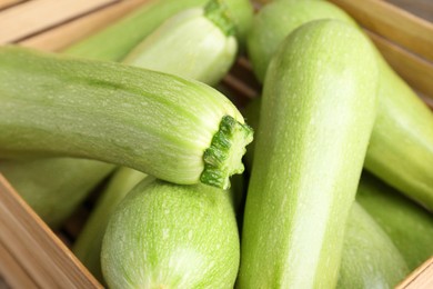 Photo of Fresh ripe zucchinis in wooden crate, closeup