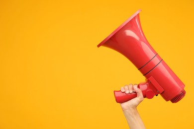 Photo of Woman holding megaphone speaker on orange background, closeup. Space for text