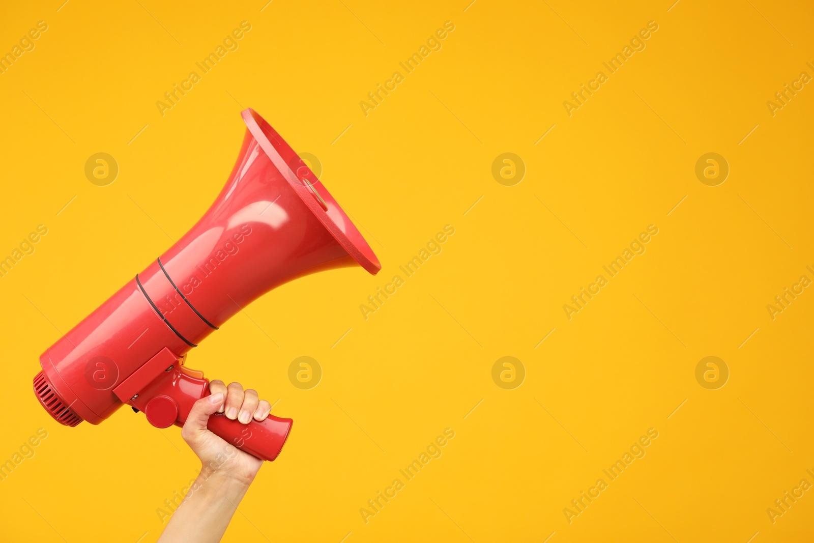 Photo of Woman holding megaphone speaker on orange background, closeup. Space for text