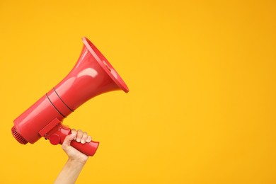 Photo of Woman holding megaphone speaker on orange background, closeup. Space for text