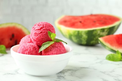 Scoops of tasty watermelon sorbet with mint in bowl on white marble table, space for text