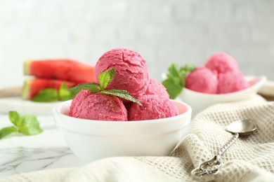 Photo of Scoops of tasty watermelon sorbet with mint in bowls and spoon on white marble table, closeup