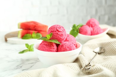 Photo of Scoops of tasty watermelon sorbet with mint in bowls and spoon on white marble table