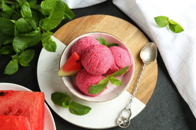 Photo of Scoops of tasty watermelon sorbet with mint, fresh fruit and spoon on grey textured table, flat lay