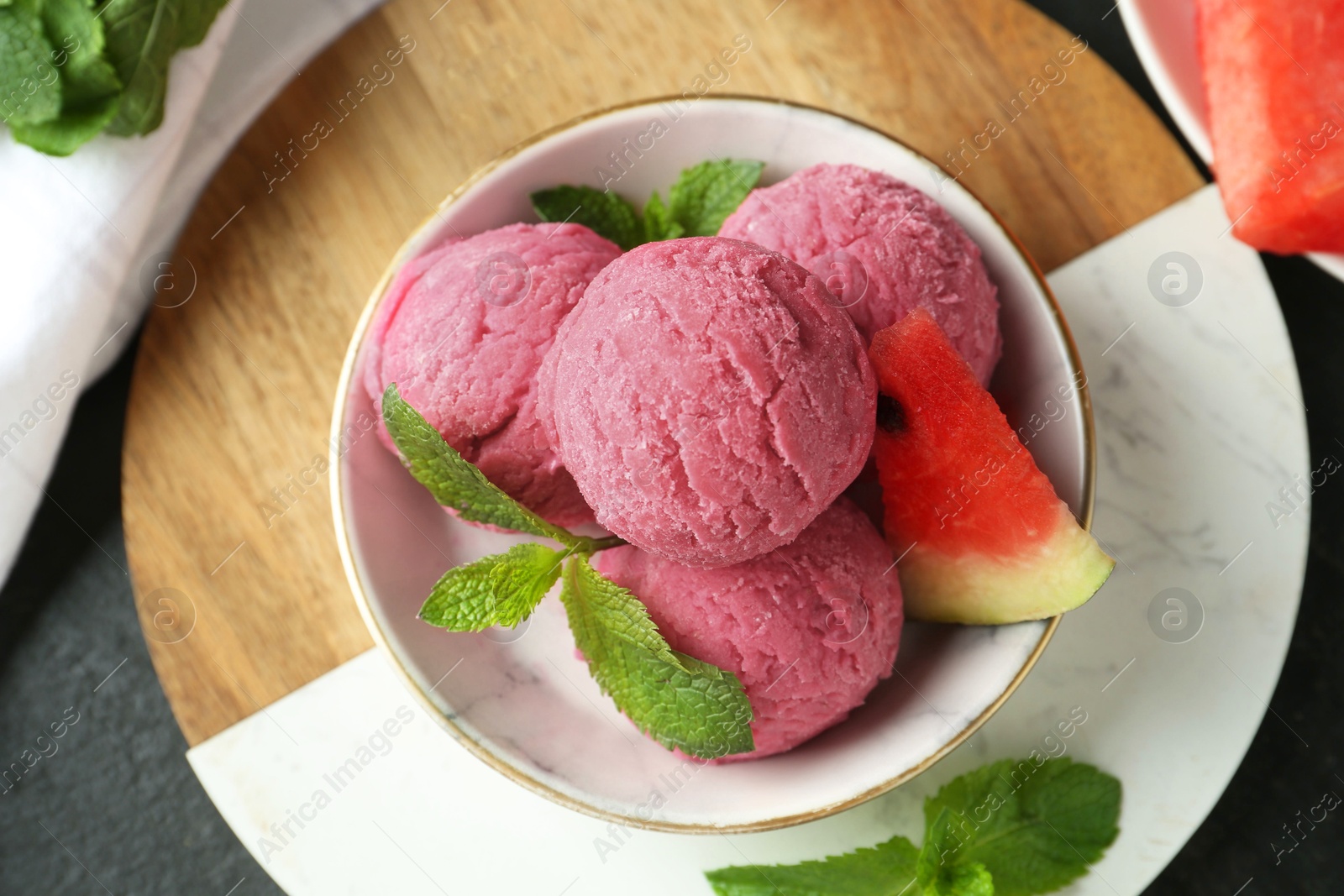 Photo of Scoops of tasty watermelon sorbet with mint and fresh fruit in bowl on grey table, flat lay