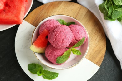 Scoops of tasty watermelon sorbet with mint and fresh fruit in bowl on grey textured table, flat lay