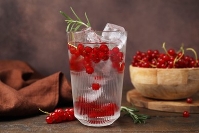 Refreshing water with red currants and rosemary in glass on wooden table, closeup