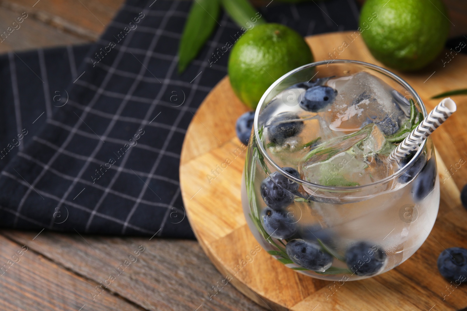 Photo of Refreshing water with blueberries and rosemary in glass on wooden table, closeup. Space for text