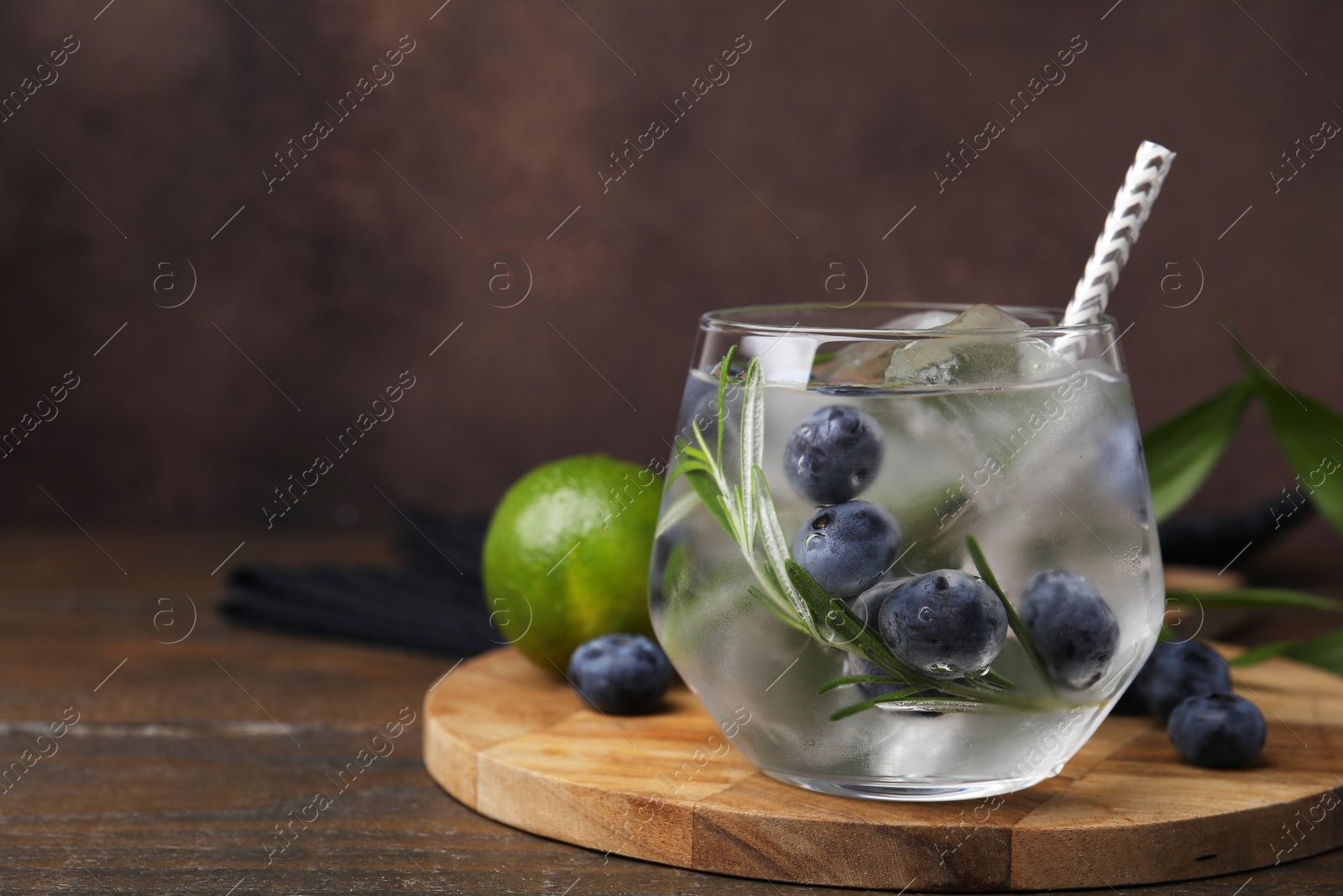 Photo of Refreshing water with blueberries and rosemary in glass on wooden table, space for text