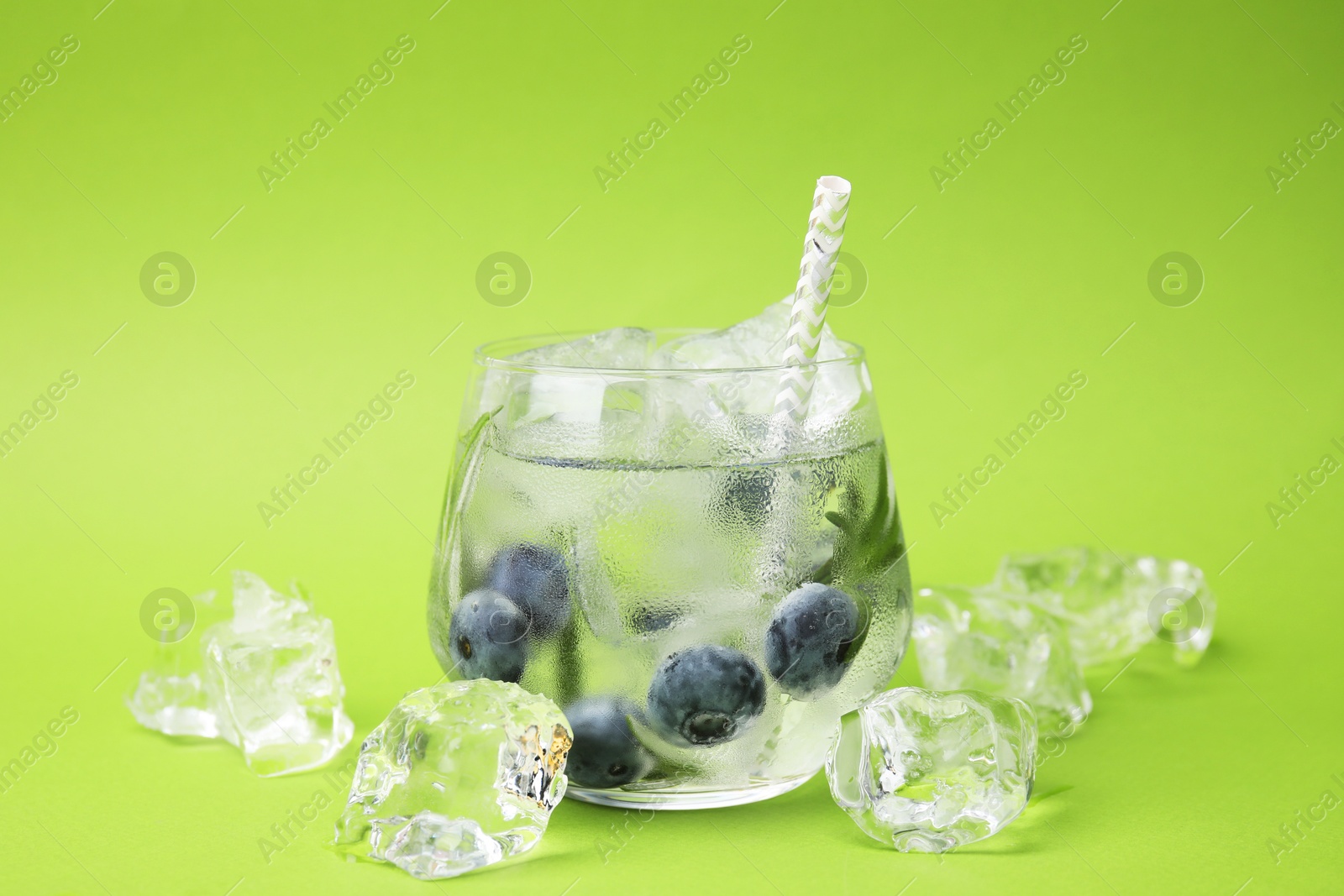 Photo of Refreshing water with blueberries, ice cubes and rosemary on green background