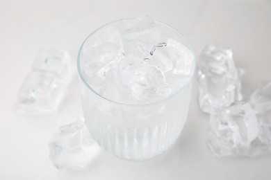 Photo of Refreshing water in glass with ice cubes on light background, closeup