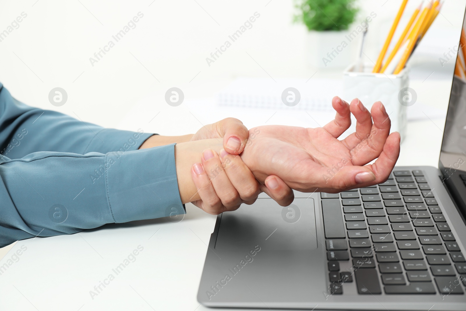 Photo of Carpal tunnel syndrome. Woman suffering from pain in wrist at desk indoors, closeup