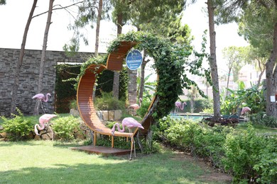 Belek, Turkey - July 25, 2024: Wooden bench in shape of heart and decorative flamingos outdoors