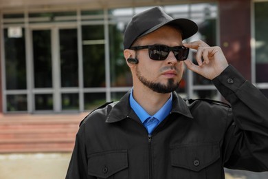 Photo of Security guard in uniform and sunglasses outdoors