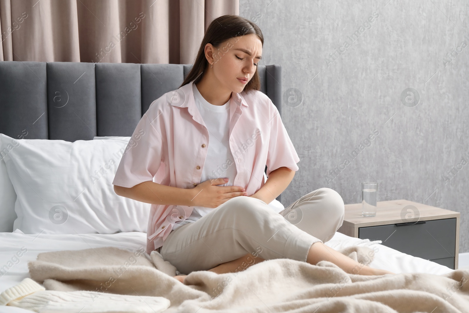 Photo of Woman suffering from menstrual pain on bed at home