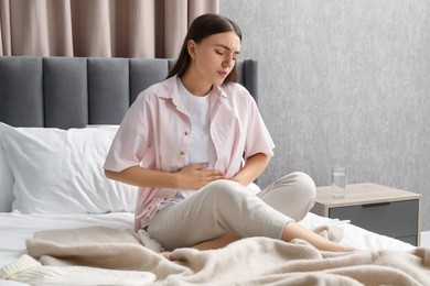 Woman suffering from menstrual pain on bed at home