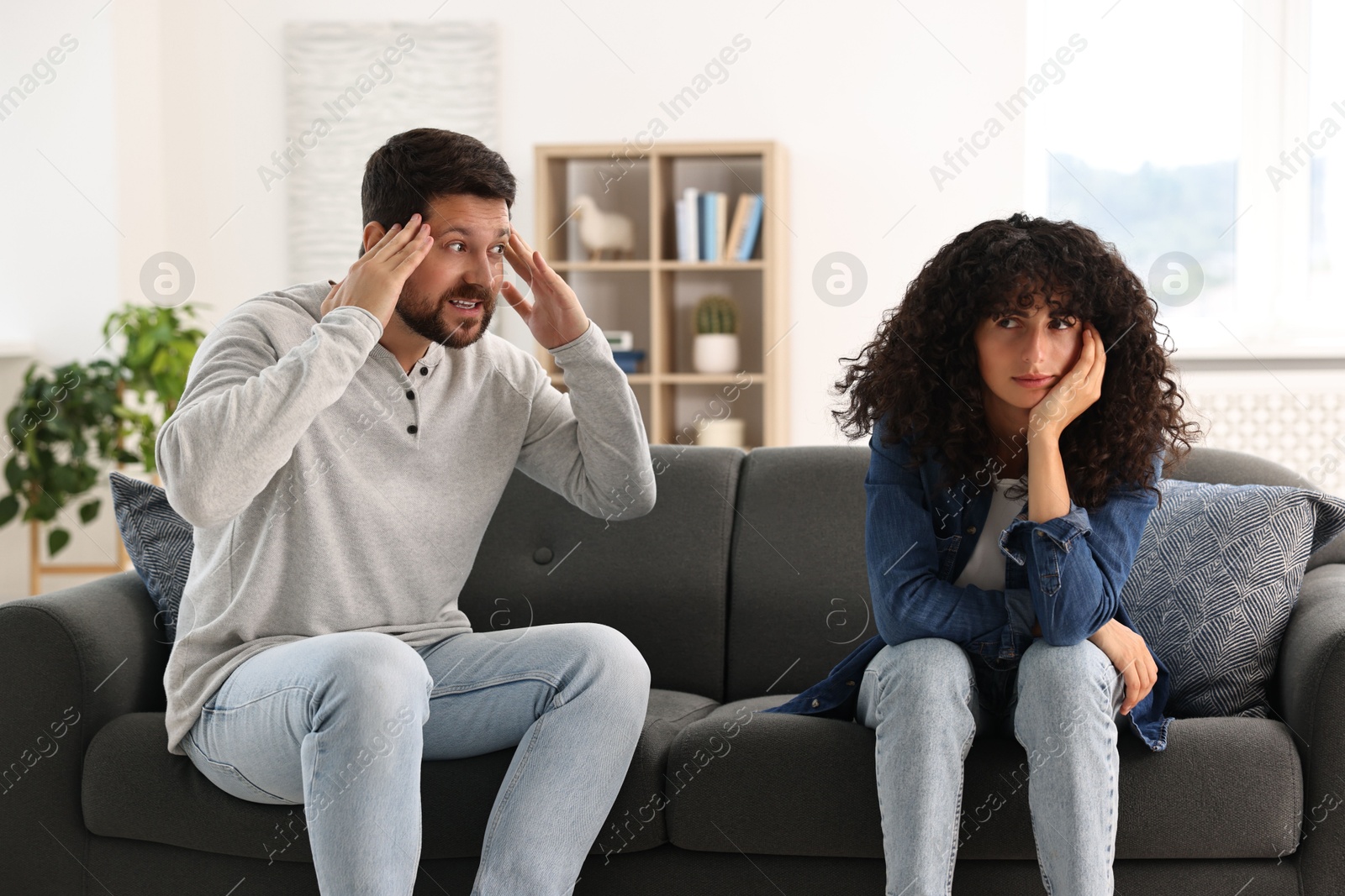 Photo of Emotional couple having quarrel on sofa at home. Relationship problems