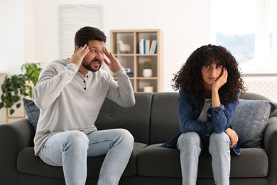 Photo of Emotional couple having quarrel on sofa at home. Relationship problems