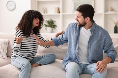 Photo of Emotional couple arguing on sofa at home. Relationship problems