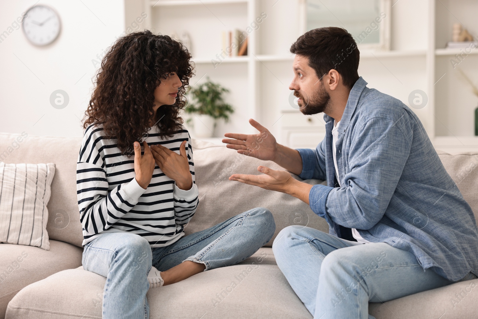 Photo of Emotional couple arguing on sofa at home. Relationship problems