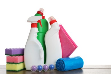 Photo of Different toilet cleaners, sponges, rag and trash bags on wooden table against white background