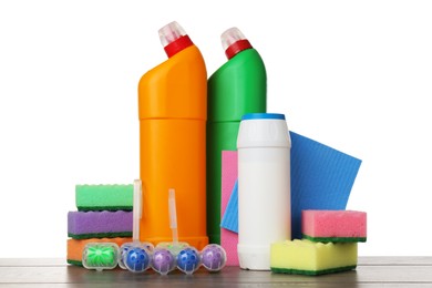 Photo of Different toilet cleaners, sponges and rag on wooden table against white background