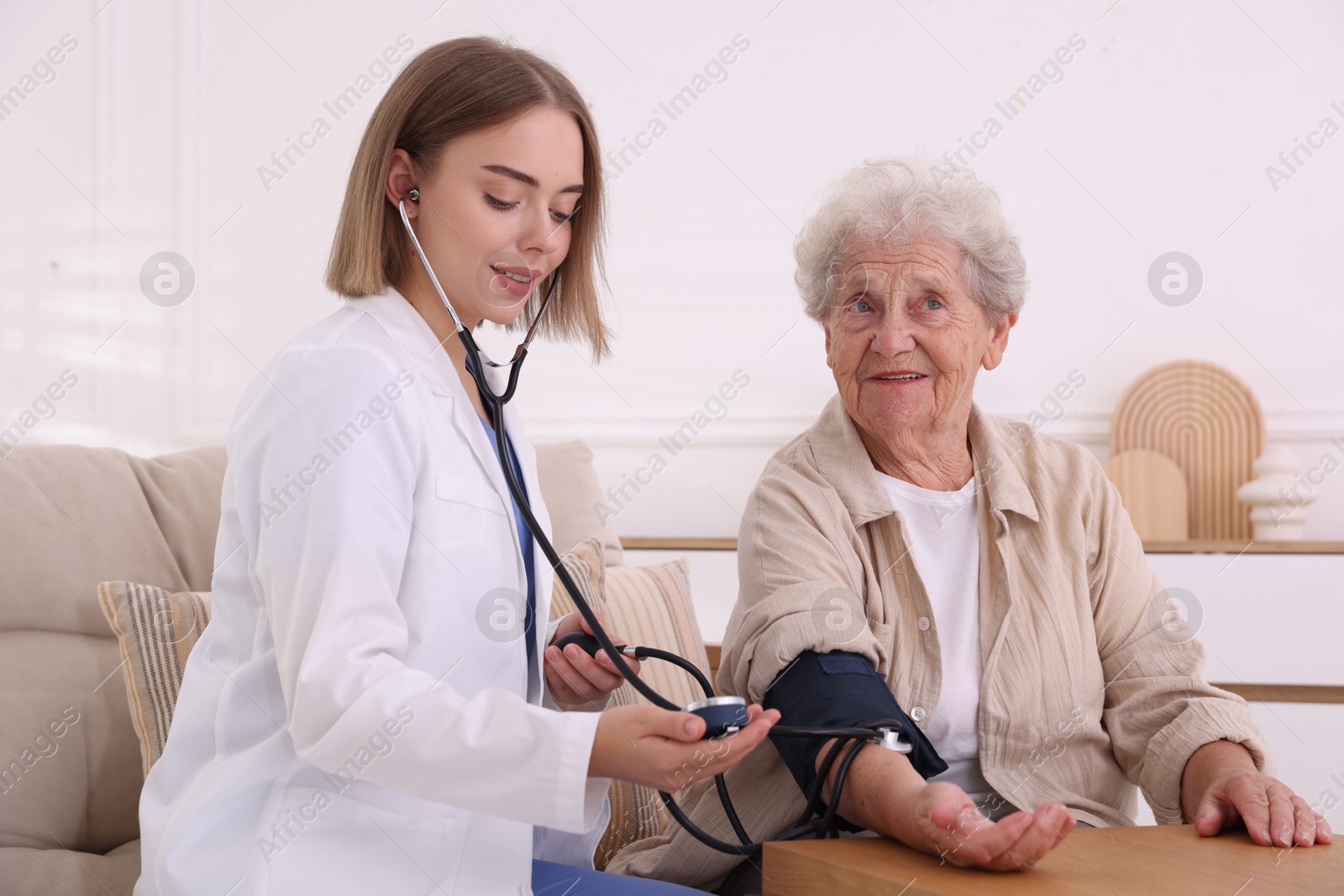 Photo of Doctor measuring patient's blood pressure at wooden table indoors