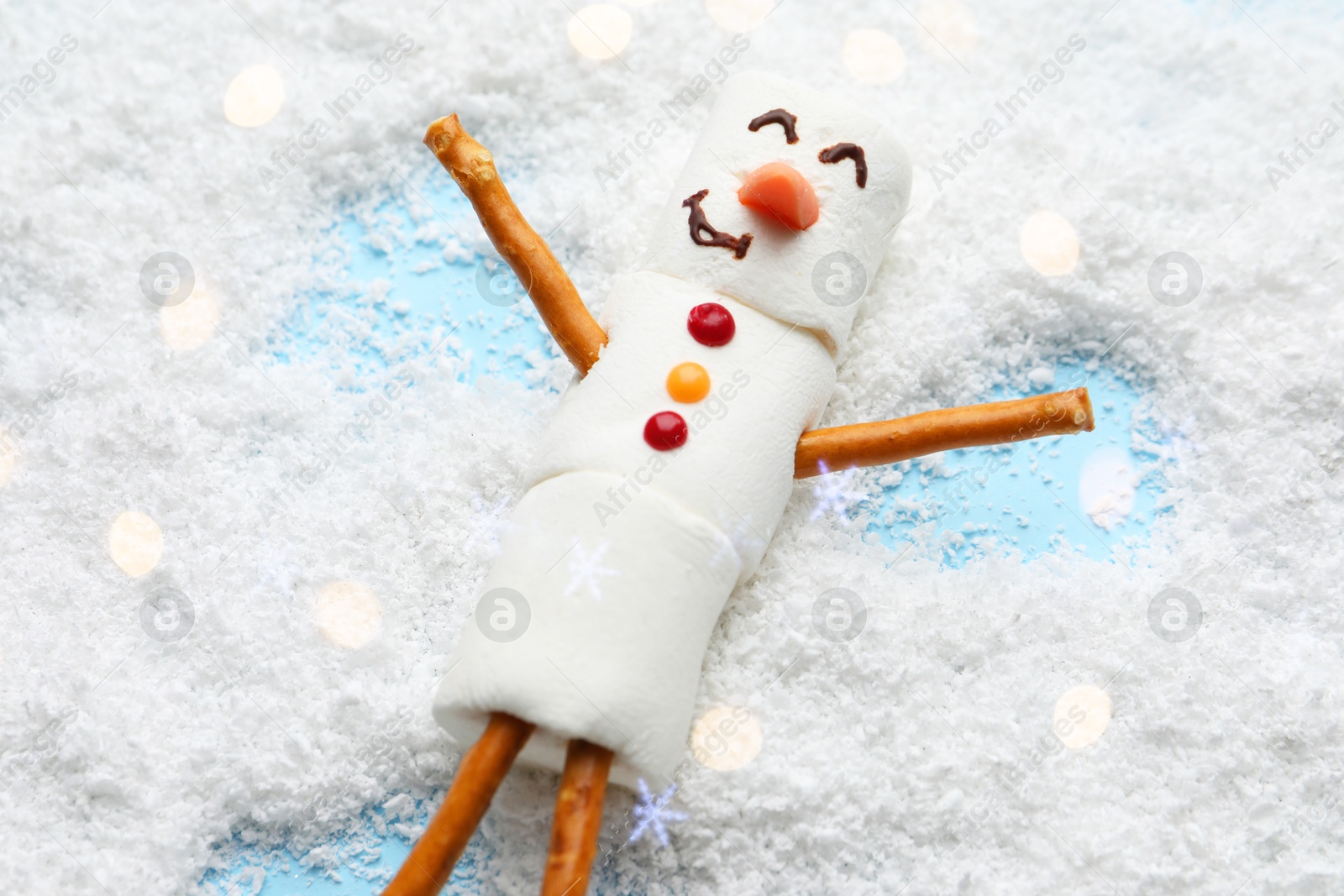 Photo of Marshmallow snowman making angel on artificial snow, above view