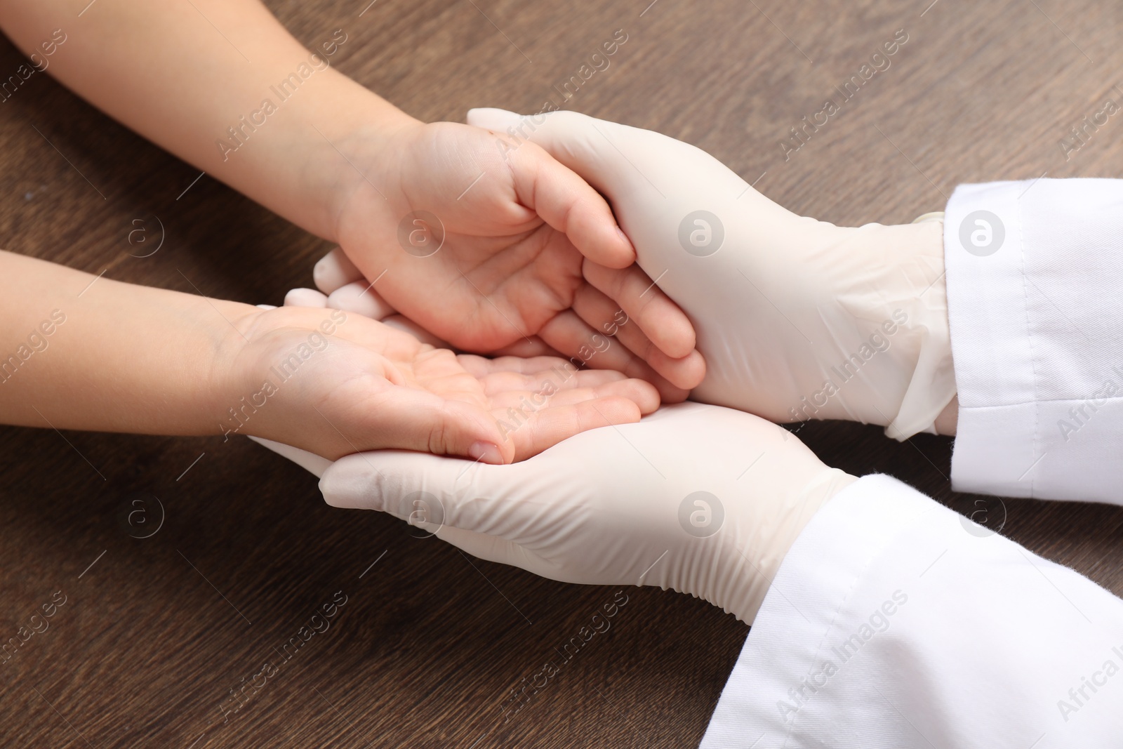 Photo of Doctor and child at wooden table, closeup