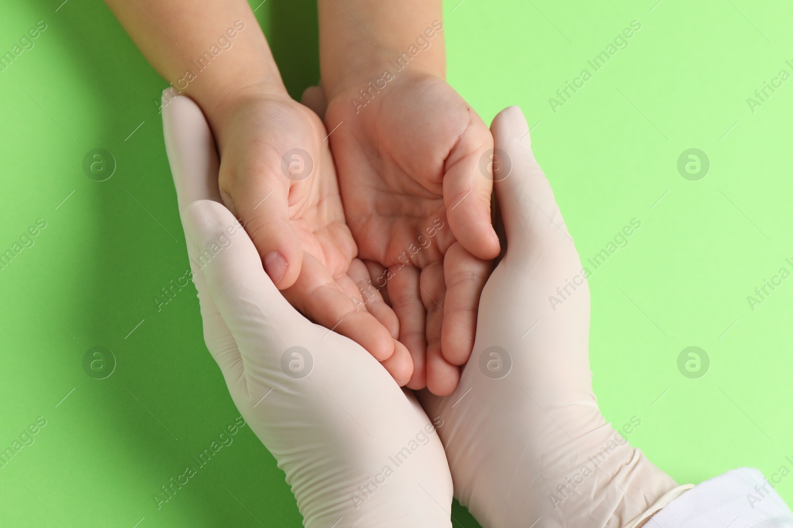 Photo of Doctor and child on light green background, top view