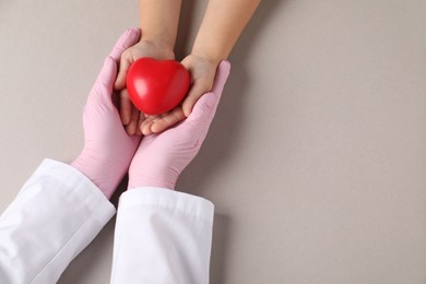 Photo of Doctor and child holding heart model on light grey background, top view. Space for text