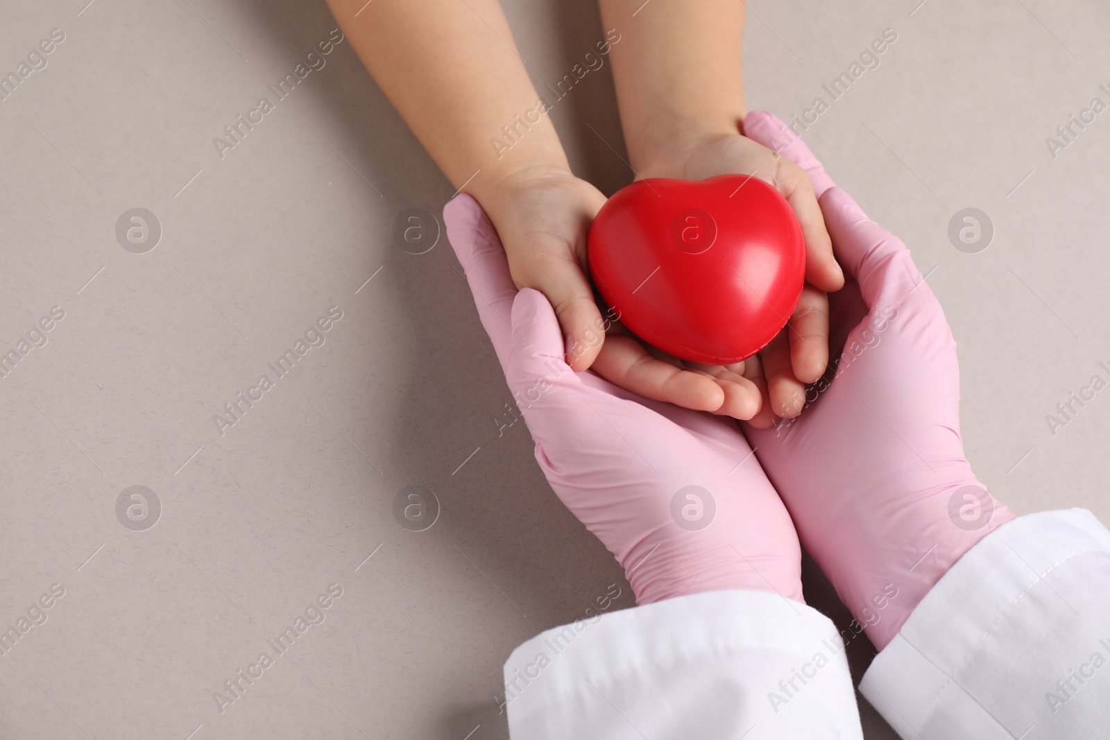 Photo of Doctor and child holding heart model on light grey background, above view. Space for text