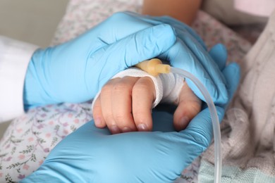 Photo of Doctor and child with intravenous drip at hospital, closeup