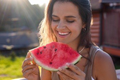 Happy woman with slice of juicy watermelon outdoors