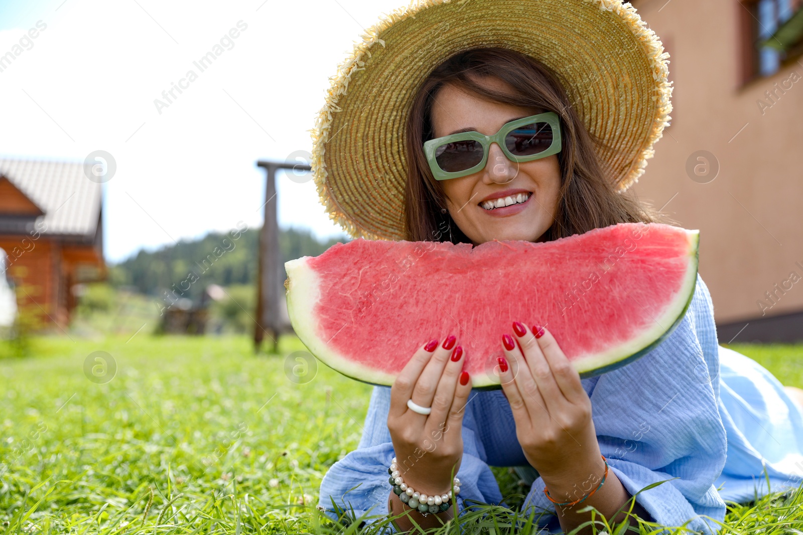 Photo of Woman with slice of juicy watermelon on green grass outdoors, space for text