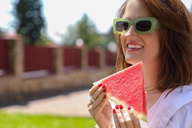 Photo of Happy woman with slice of juicy watermelon outdoors, space for text