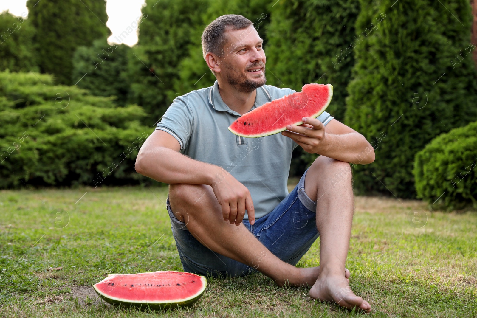 Photo of Happy man with slice of juicy watermelon outdoors