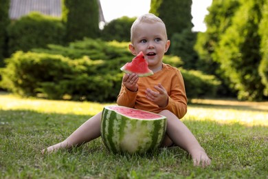 Photo of Cute little baby eating juicy watermelon on green grass outdoors