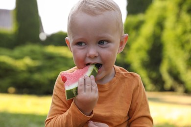 Cute little baby eating juicy watermelon outdoors