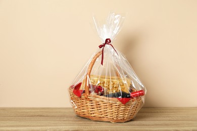 Photo of Wicker gift basket on wooden table against beige background