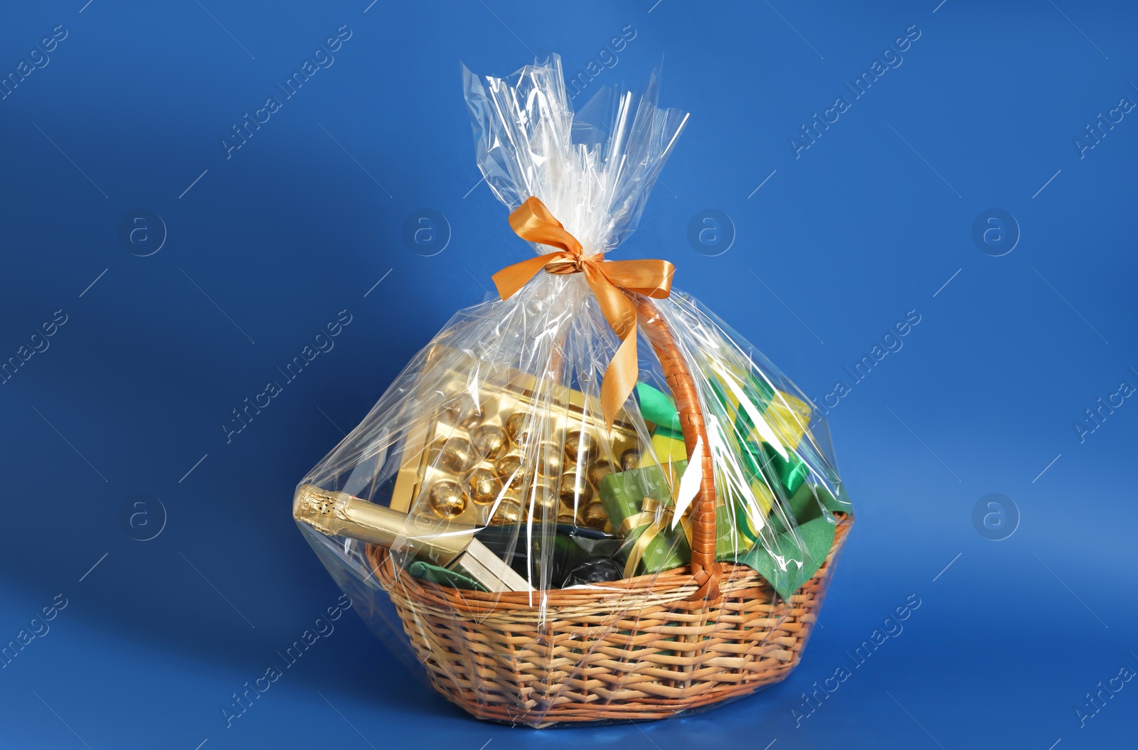 Photo of Wicker gift basket with wine on blue background