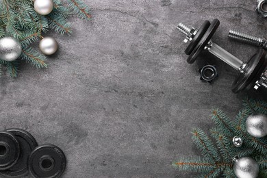 Photo of Barbell, dumbbell parts and Christmas decor on grey background, flat lay. Space for text