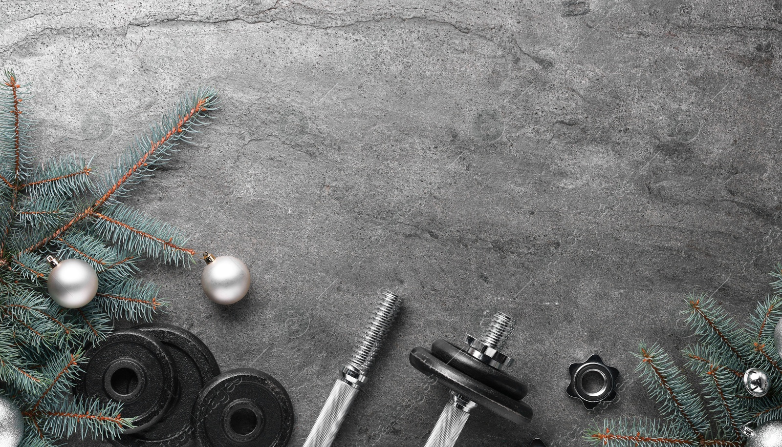 Photo of Barbell, dumbbell parts and Christmas decor on grey background, flat lay. Space for text