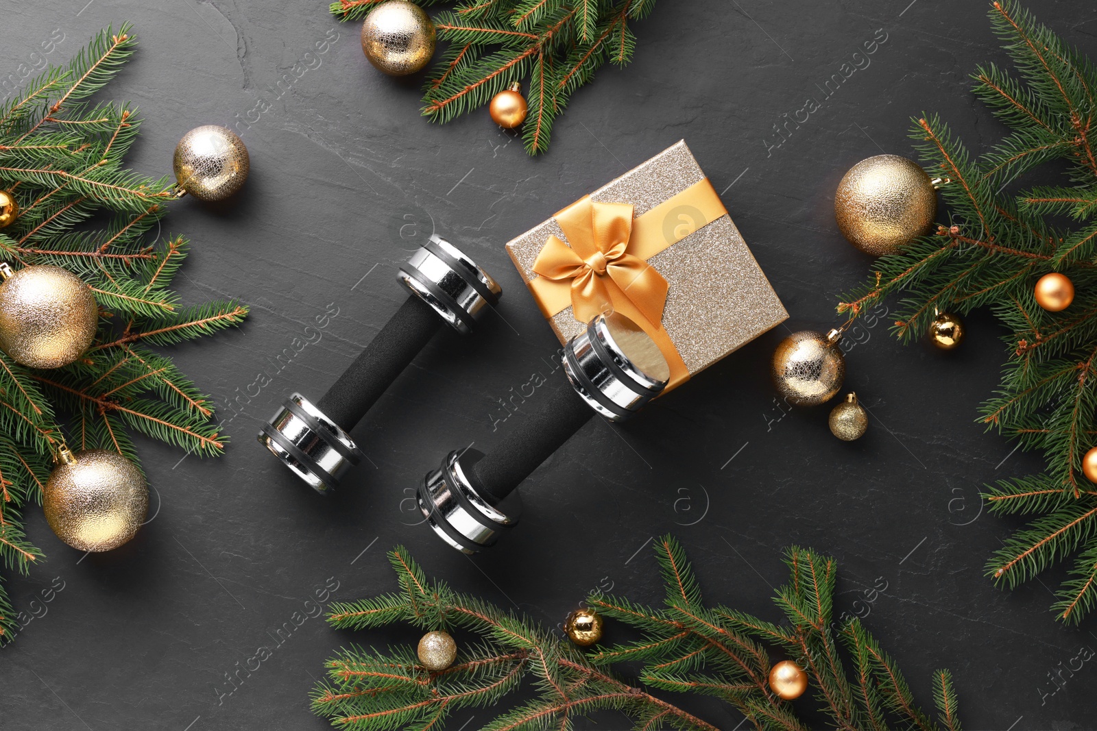 Photo of Dumbbells, gift box and Christmas decor on black background, flat lay